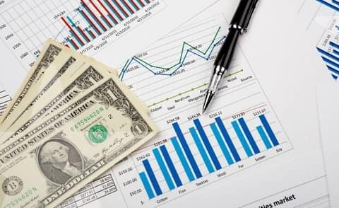 Economic charts and graphs with dollar bills and a pen